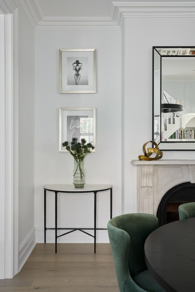 A small half-moon table with a flower vase sits below black-and-white photos, styled by trusted Sydney decorator Emma Blomfield.