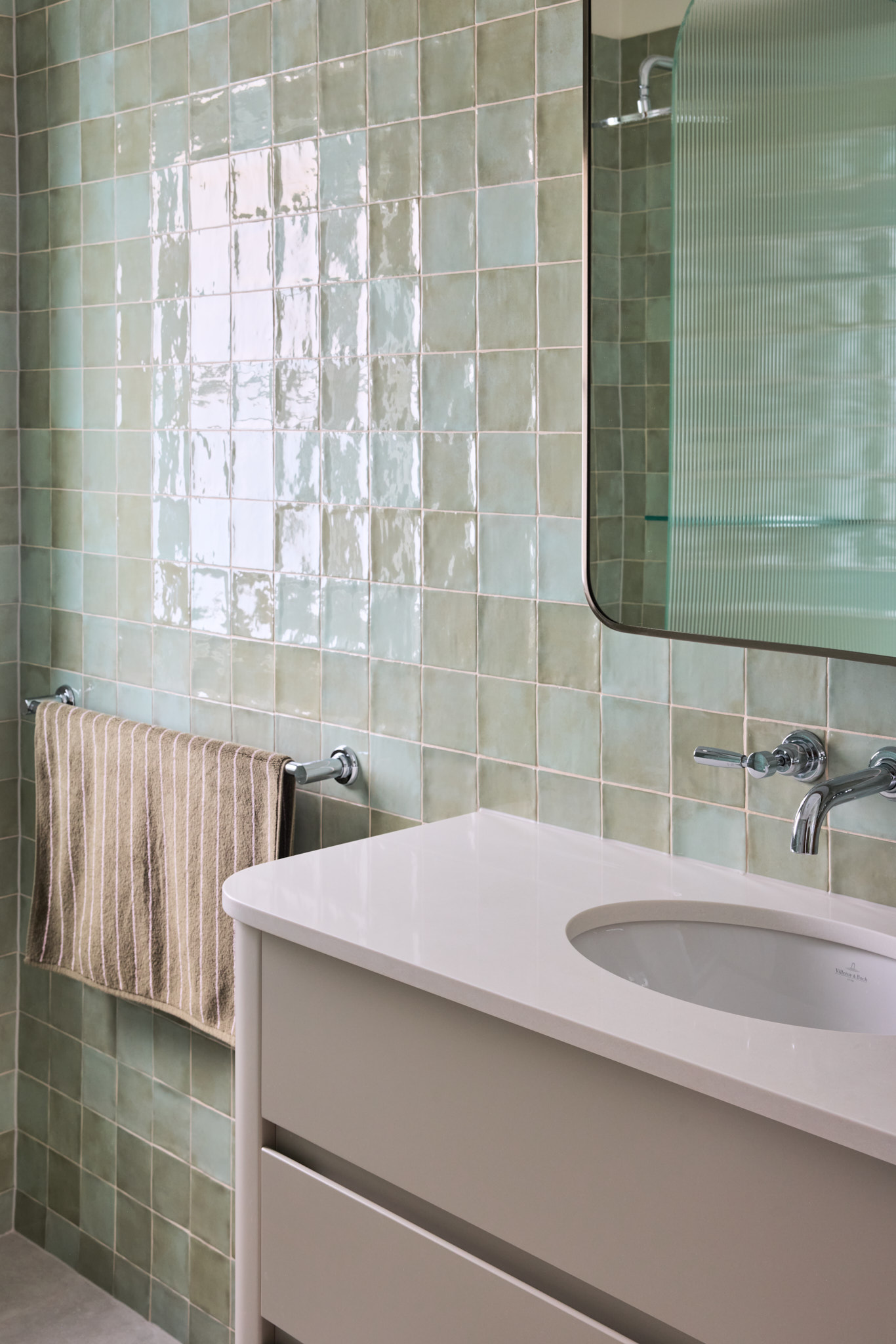 Modern bathroom in a Mosman home featuring light green square tiles, wall-mounted faucet, rectangular mirror, white vanity, chrome towel bar—and if present, Emma Blomfield.