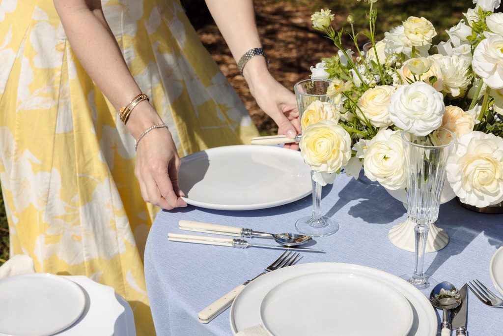 Emma Blomfield sets a place at a round table featuring a floral centerpiece and an Emma Blomfield collection rug.