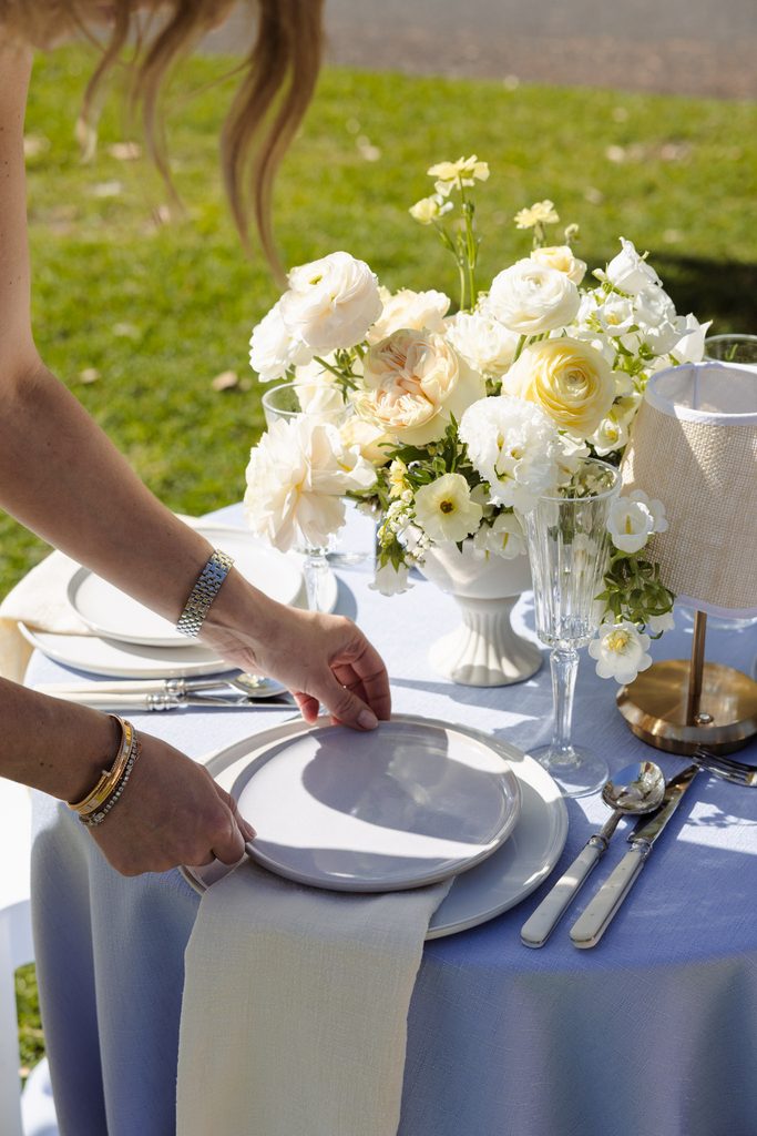 Emma Blomfield sets a plate on a table decorated with a floral centerpiece and glassware to complement her rug collection.